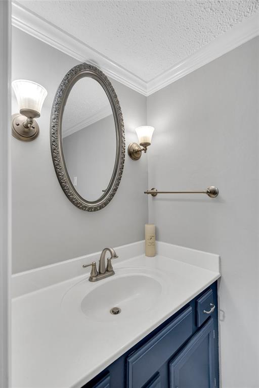 bathroom featuring a textured ceiling, crown molding, and vanity