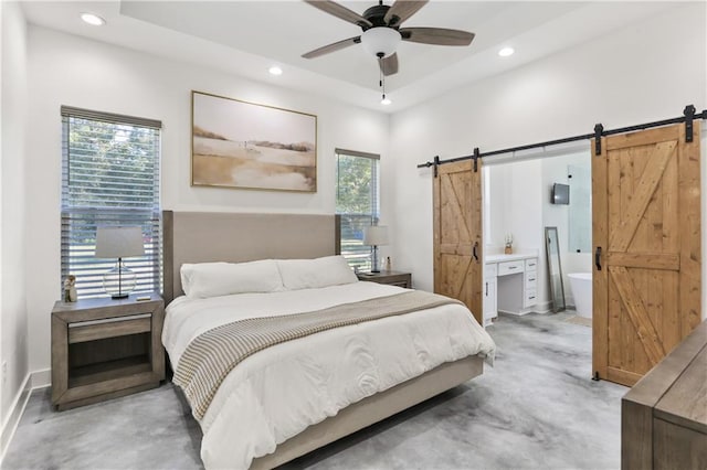 bedroom featuring a barn door, ensuite bath, and ceiling fan