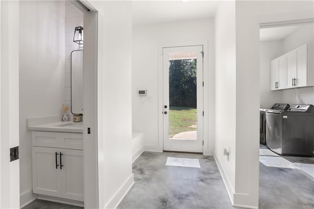 doorway with washing machine and clothes dryer and sink