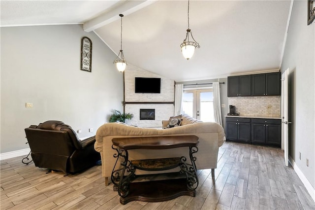 living room featuring lofted ceiling with beams, a large fireplace, light wood-type flooring, and french doors