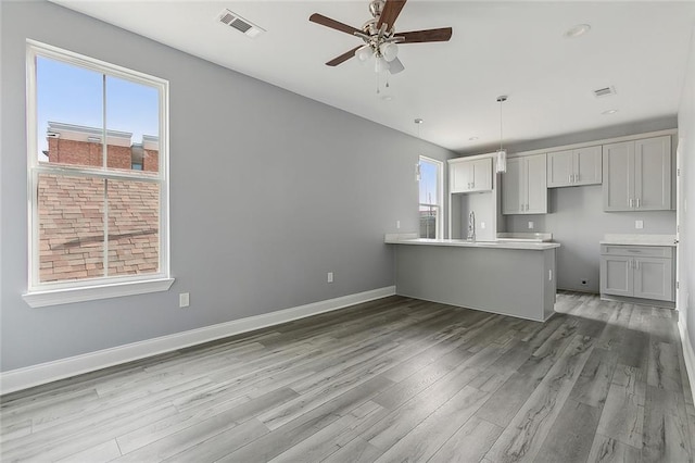 kitchen featuring ceiling fan, sink, kitchen peninsula, hardwood / wood-style floors, and decorative light fixtures