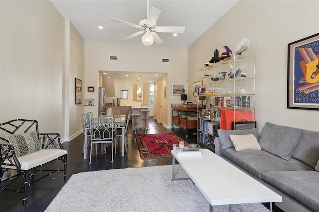 living room featuring a towering ceiling, ceiling fan, and dark hardwood / wood-style flooring