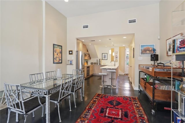 dining space featuring a towering ceiling and sink