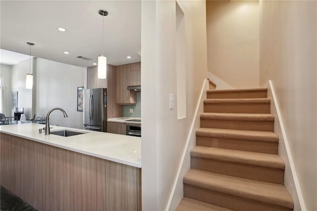 kitchen featuring hanging light fixtures, sink, backsplash, exhaust hood, and stainless steel appliances