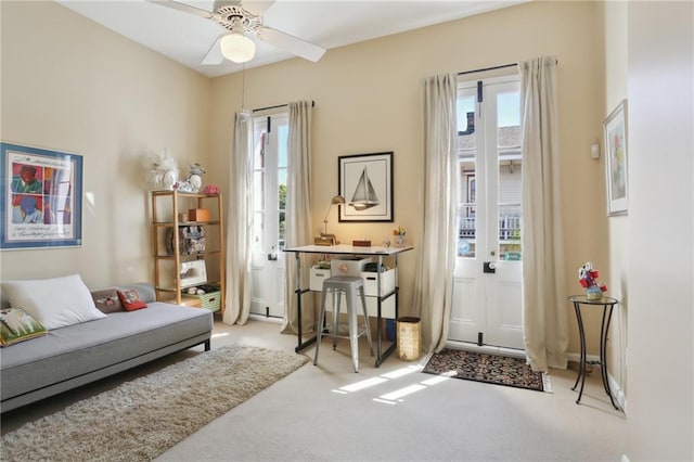 living area featuring light carpet and ceiling fan