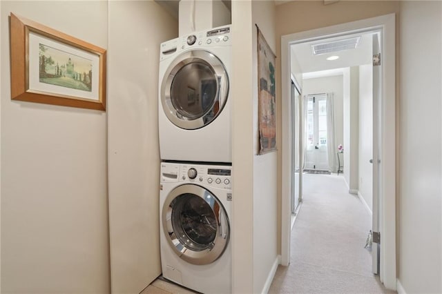 washroom with light colored carpet and stacked washer / drying machine