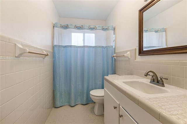 bathroom with tile walls, walk in shower, tile patterned floors, vanity, and toilet