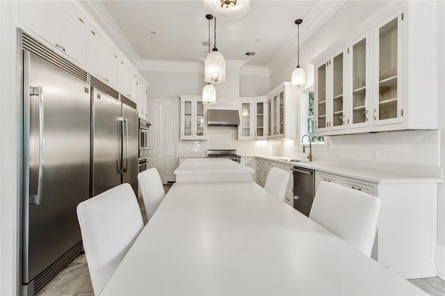 kitchen with hanging light fixtures, white cabinetry, tasteful backsplash, ornamental molding, and sink