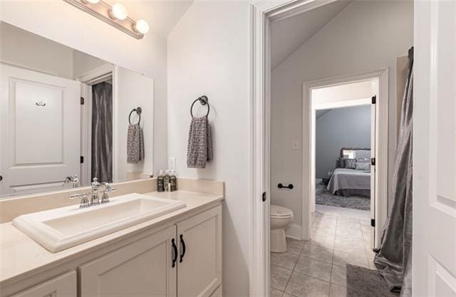 bathroom featuring vanity, vaulted ceiling, toilet, and tile patterned floors