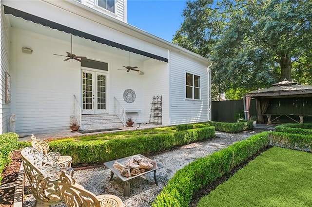 view of exterior entry with ceiling fan, french doors, a patio area, and a lawn