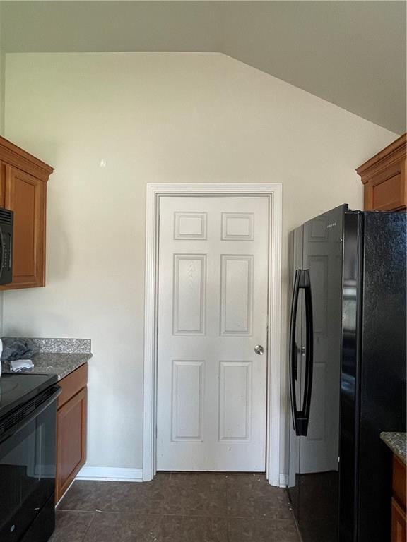 kitchen featuring dark tile patterned floors, black appliances, and vaulted ceiling