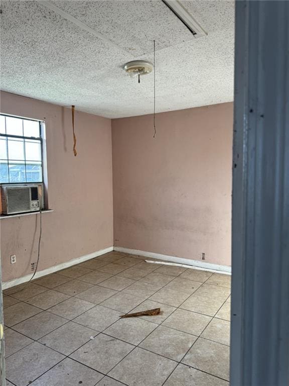 unfurnished room with a textured ceiling, cooling unit, and light tile patterned floors