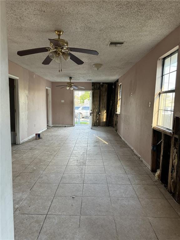 unfurnished room with ceiling fan, a textured ceiling, and light tile patterned floors