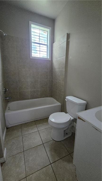 full bathroom featuring tile patterned flooring, tiled shower / bath combo, vanity, and toilet