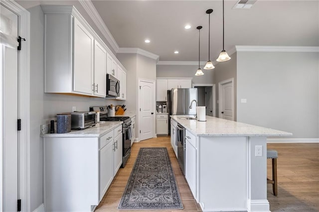 kitchen with hanging light fixtures, an island with sink, white cabinetry, and stainless steel appliances