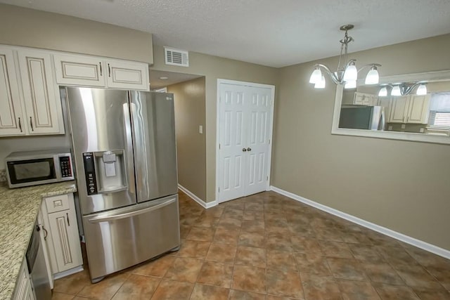 kitchen featuring decorative light fixtures, a notable chandelier, stainless steel appliances, and light stone countertops