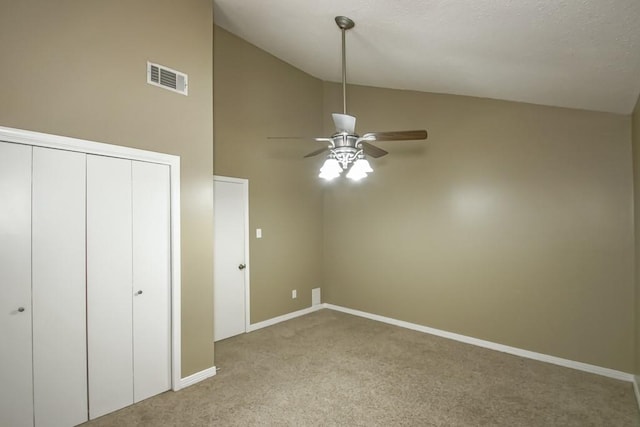 unfurnished bedroom with light carpet, a closet, ceiling fan, and high vaulted ceiling