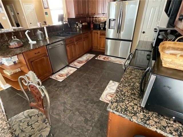 kitchen with dark stone countertops, dark tile patterned flooring, tasteful backsplash, kitchen peninsula, and stainless steel appliances