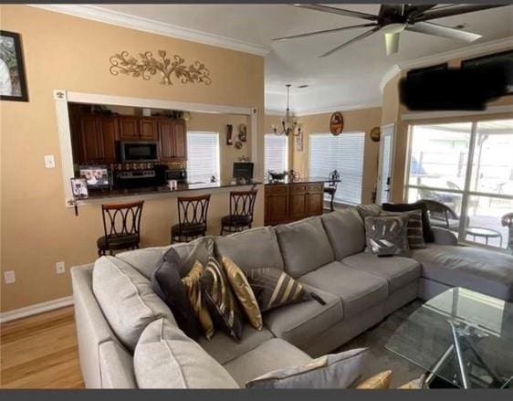 living room featuring ceiling fan with notable chandelier, crown molding, and light hardwood / wood-style flooring