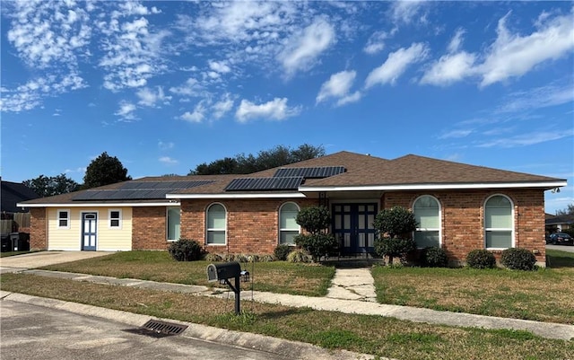 ranch-style home with french doors, a front yard, and solar panels