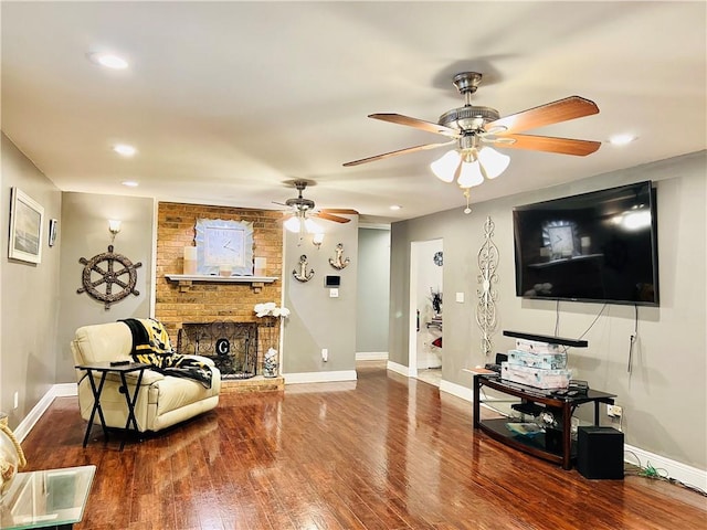 living room with wood-type flooring, a brick fireplace, and ceiling fan