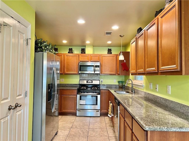 kitchen with light tile patterned flooring, sink, stone countertops, pendant lighting, and stainless steel appliances