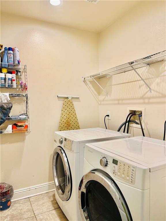 clothes washing area with washer and clothes dryer and light tile patterned floors