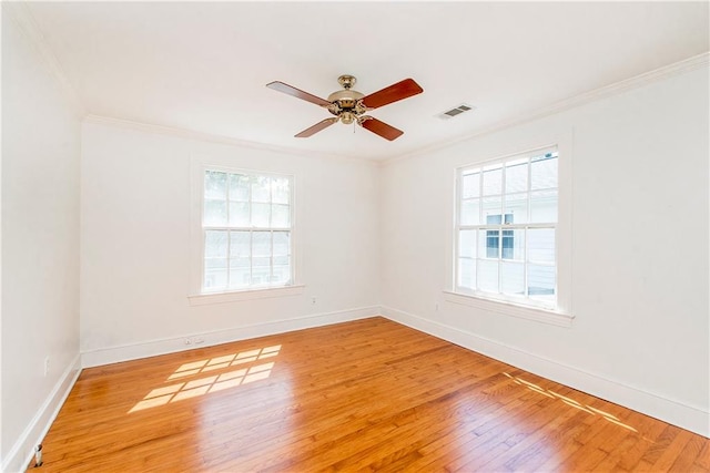 empty room with ornamental molding, a wealth of natural light, wood-type flooring, and ceiling fan