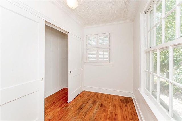 unfurnished bedroom with a closet, light hardwood / wood-style floors, and crown molding