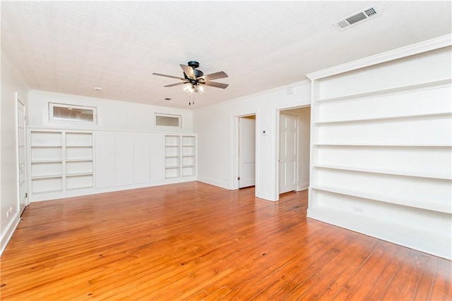 spare room with wood-type flooring, crown molding, built in shelves, and ceiling fan