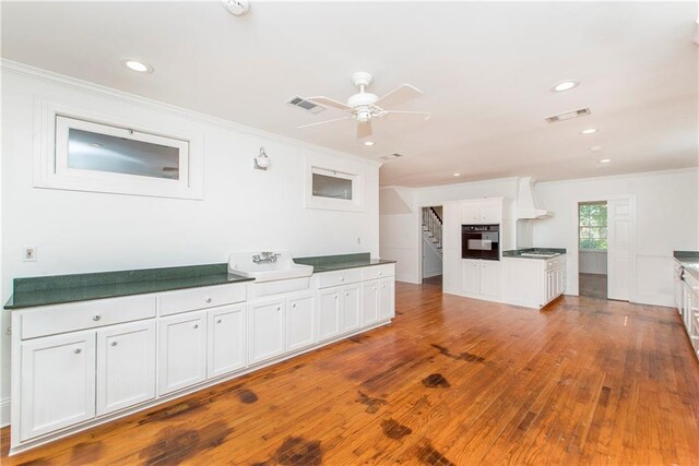 kitchen featuring white cabinetry, black oven, ceiling fan, hardwood / wood-style flooring, and ornamental molding