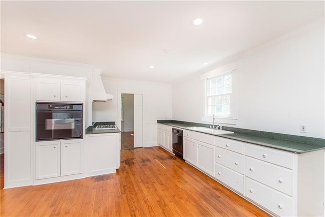 kitchen featuring black appliances, sink, light hardwood / wood-style flooring, and white cabinets