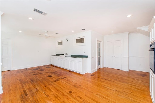 unfurnished living room with light wood-type flooring, ornamental molding, and ceiling fan