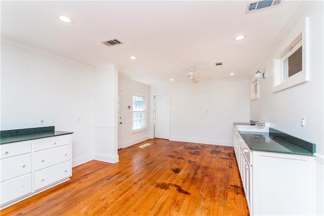 kitchen with white cabinetry, crown molding, ceiling fan, light hardwood / wood-style flooring, and sink