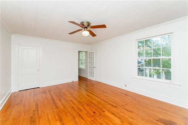 empty room with a healthy amount of sunlight, wood-type flooring, crown molding, and ceiling fan