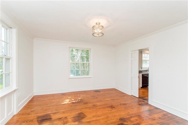 spare room with a healthy amount of sunlight, crown molding, and hardwood / wood-style flooring