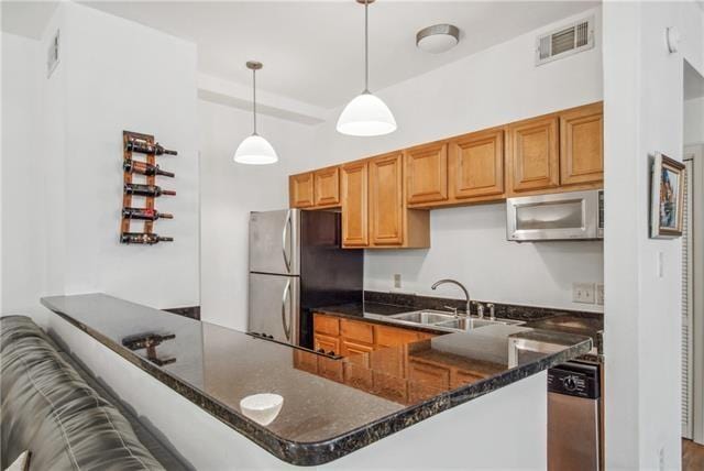 333 Julia St Unit 508, New Orleans, LA 70130 - kitchen with appliances with stainless steel finishes, a sink, a peninsula, and dark stone counters