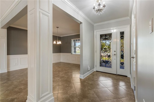 tiled foyer entrance featuring ornamental molding and an inviting chandelier