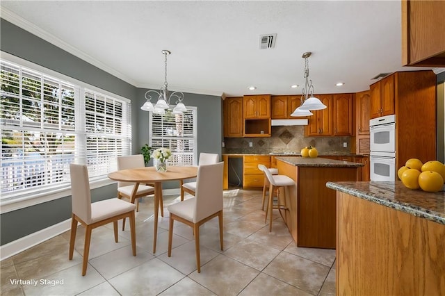 dining room with an inviting chandelier, light tile patterned floors, and ornamental molding