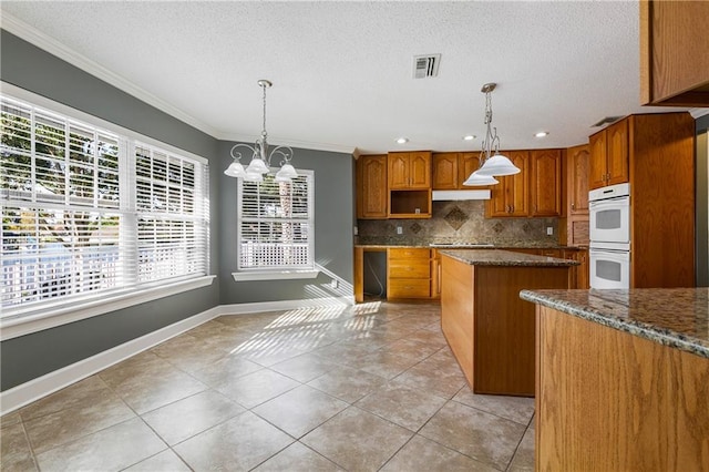 kitchen with white double oven, decorative light fixtures, a kitchen island, and dark stone countertops