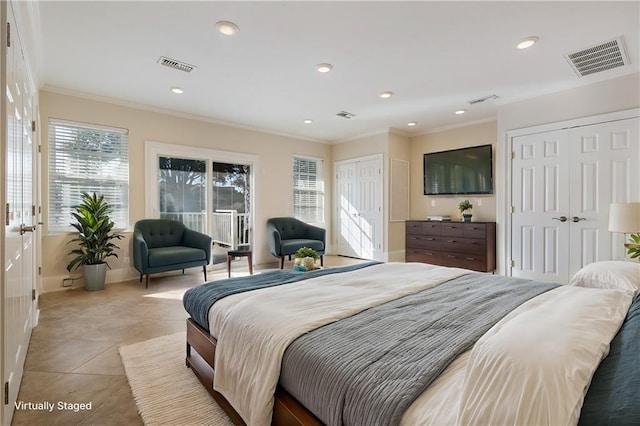 bedroom featuring light tile patterned flooring, ornamental molding, and two closets