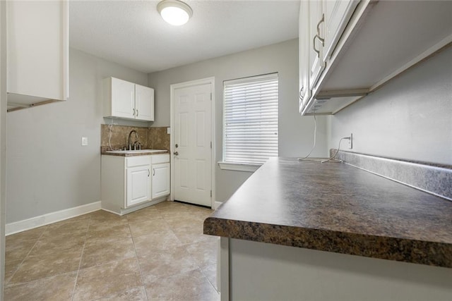 kitchen with sink, white cabinetry, tasteful backsplash, light tile patterned flooring, and kitchen peninsula