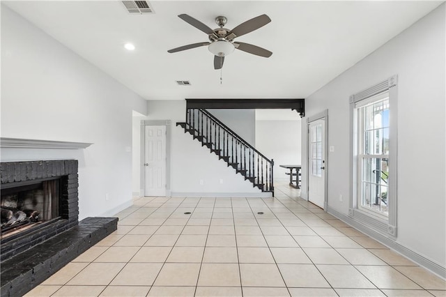 unfurnished living room with ceiling fan, a fireplace, and light tile patterned floors