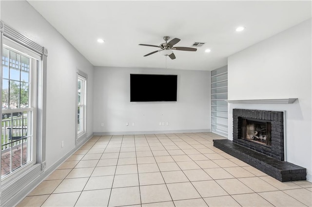 unfurnished living room with a brick fireplace, ceiling fan, light tile patterned flooring, and built in features