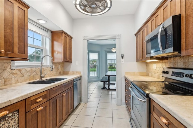 kitchen featuring ceiling fan, light tile patterned floors, sink, backsplash, and stainless steel appliances