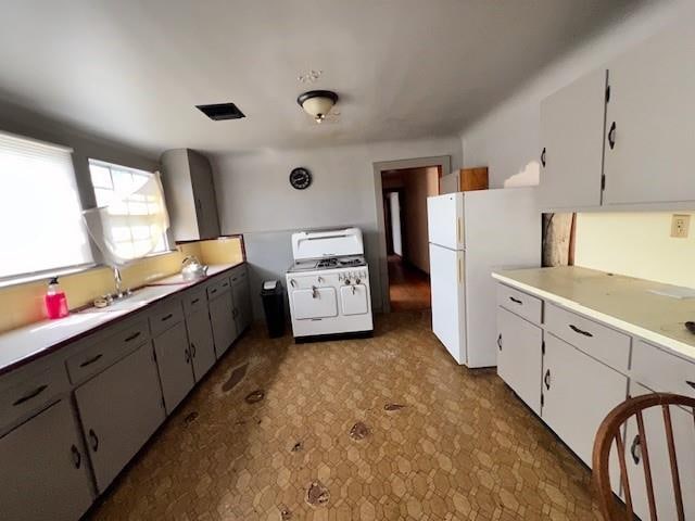 kitchen featuring sink, white appliances, and white cabinetry