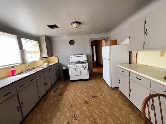kitchen featuring light countertops, a sink, washer / dryer, freestanding refrigerator, and gas stove
