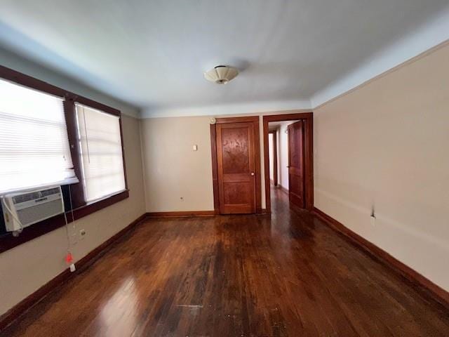 empty room with cooling unit, baseboards, and dark wood finished floors