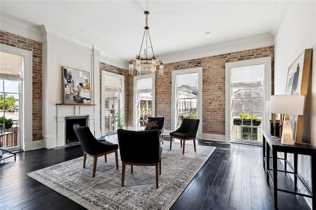 dining room featuring ornamental molding, a notable chandelier, brick wall, and dark wood-type flooring