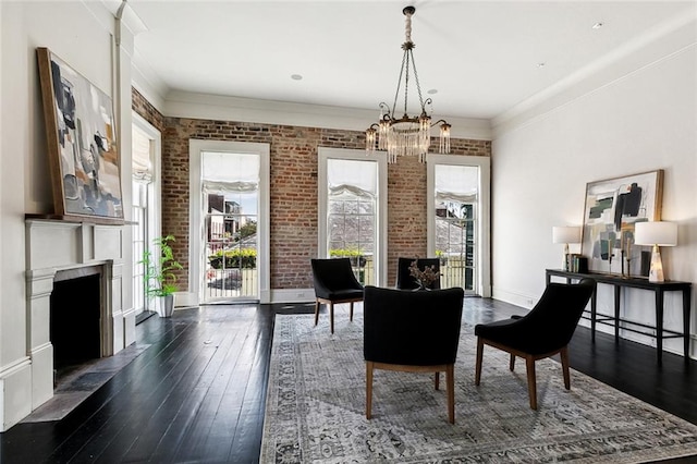 dining room with brick wall, dark hardwood / wood-style floors, a chandelier, and a healthy amount of sunlight